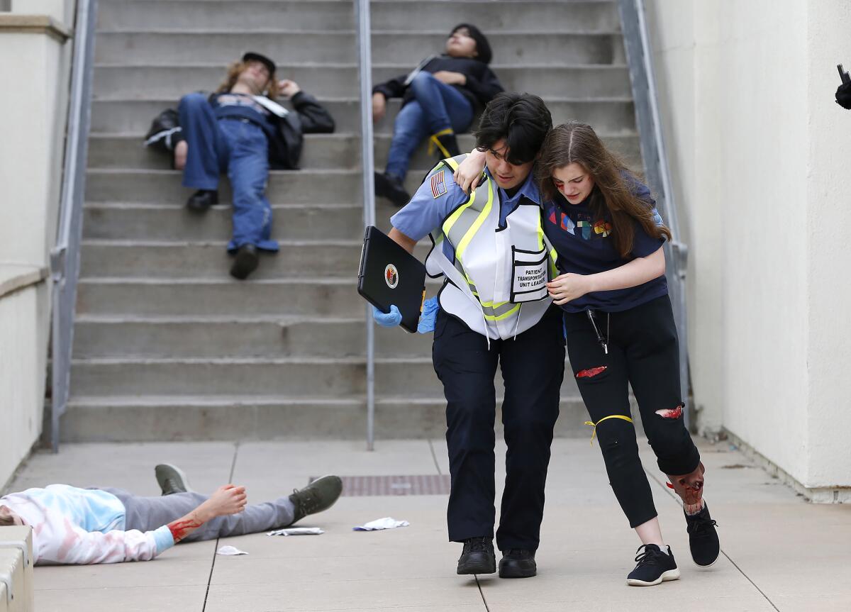 EMT student Cristian Castro, left, carries acting student Katherine Jordan to safety.