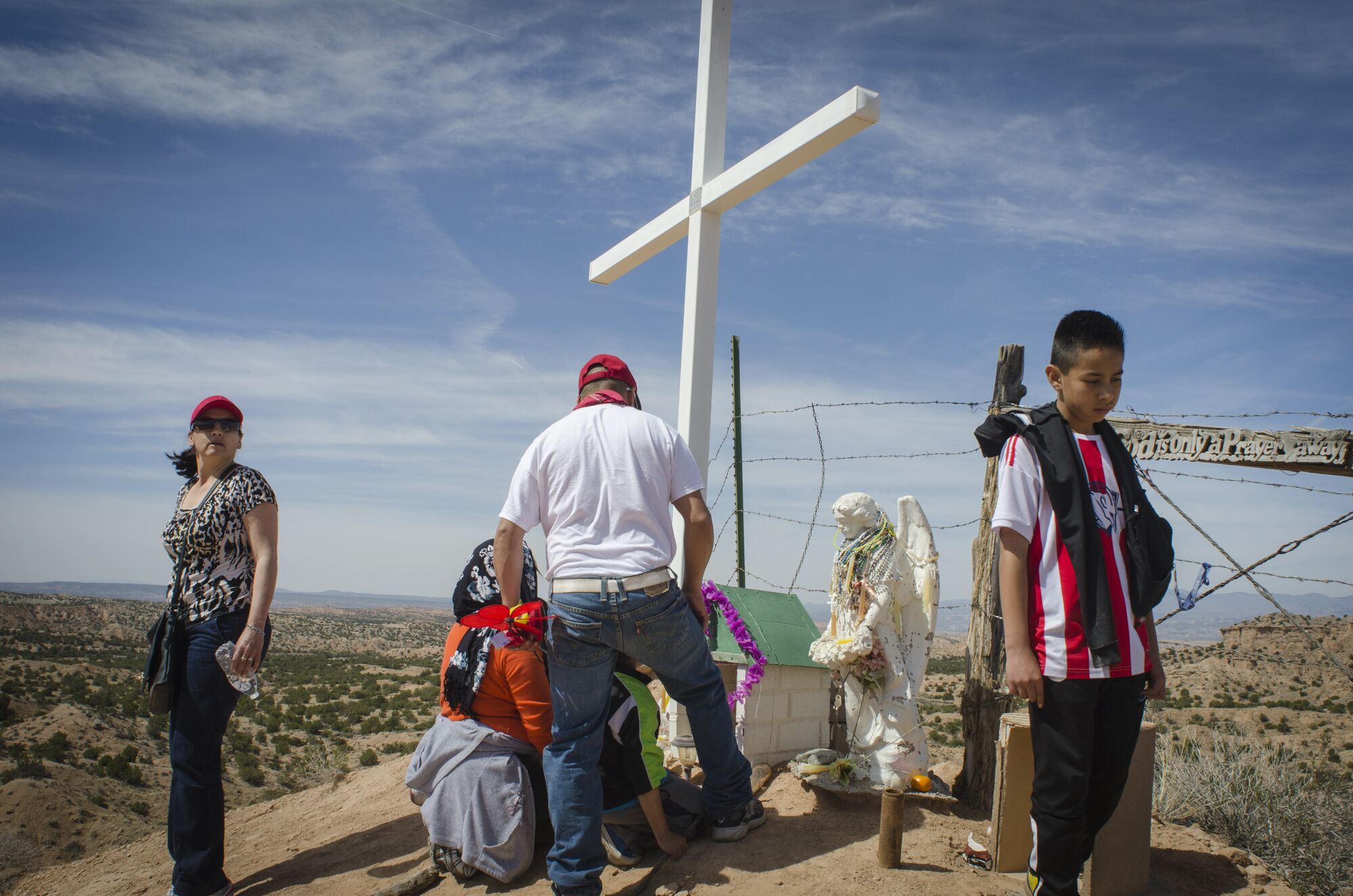 A family from Chihuahua, Mexico prays at a hilltop shrine on the road from Nambé, New Mexico to El Santuario de Chimayo