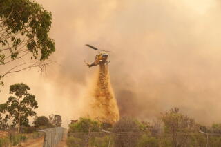 A helicopter drops fire retardant on a fire near Wooroloo, northeast of Perth, Australia.
