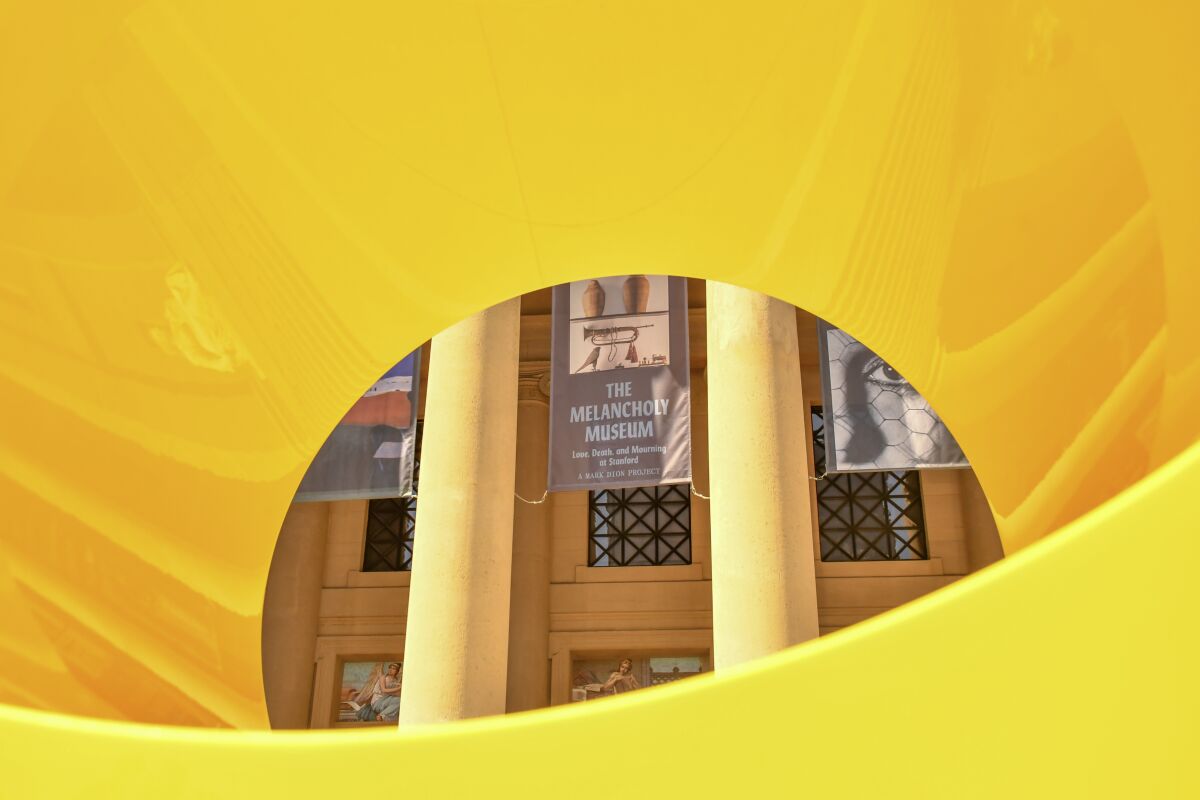 A banner advertising "The Melancholy Museum" hangs on a building with columns, seen through a yellow aperture.