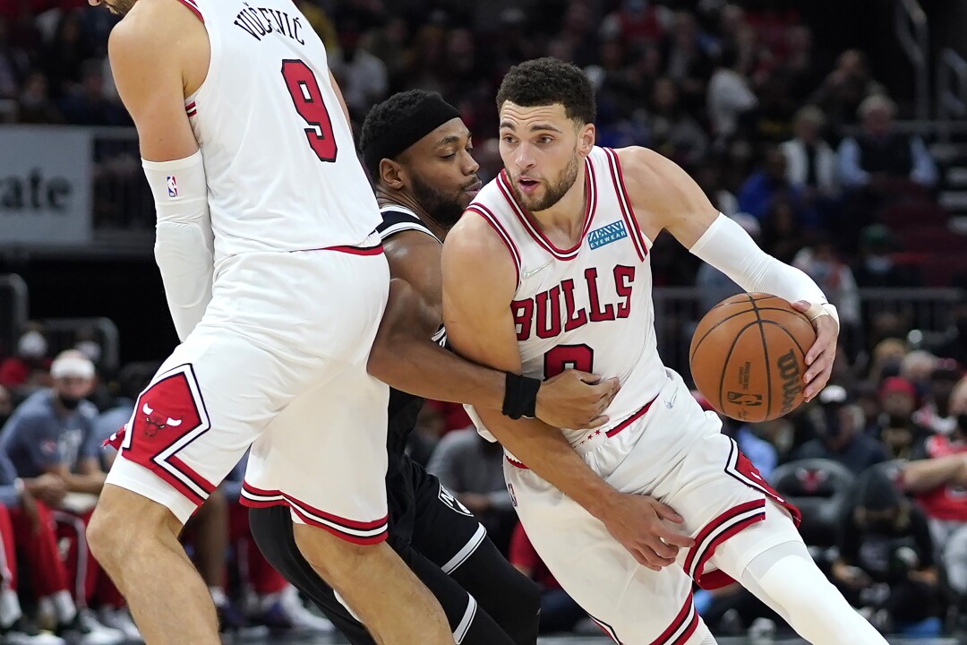 Bulls guard Zach LaVine drives around a screen by teammate Nikola Vucevic to get past Nets guard Bruce Brown.