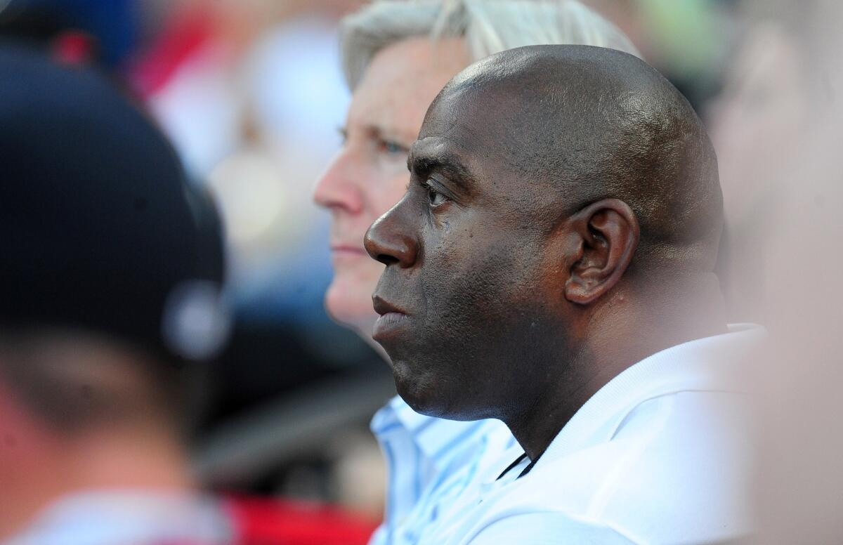 Lakers great Magic Johnson watches the Dodgers play the Atlanta Braves in Game 2 of the National League division series on Friday. Johnson says L.A. sports fans will once again shift their focus to the Lakers once baseball season ends.