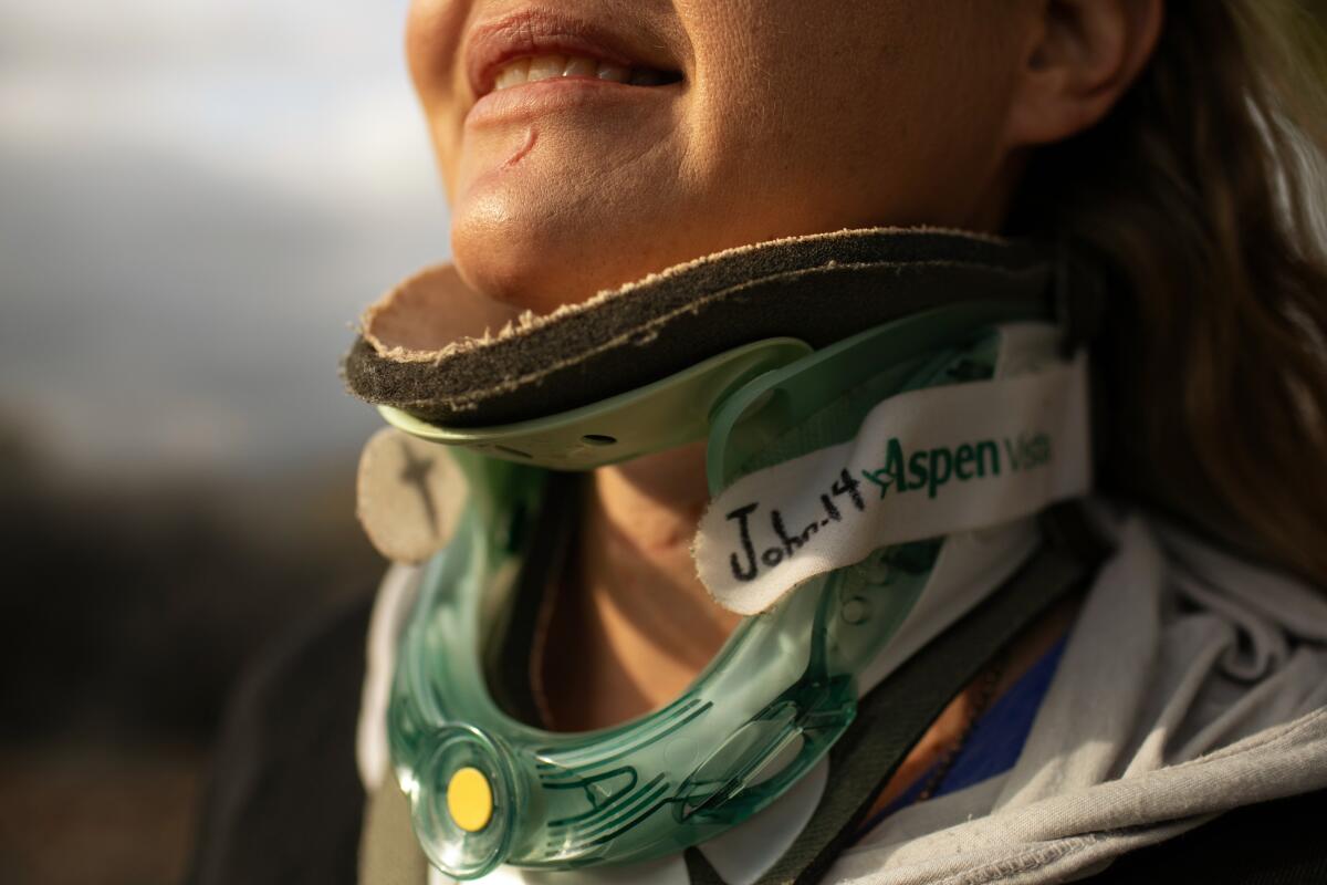 A close-up view of a women's shoulders, chin and smiling mouth, while a neck brace is covering her neck.