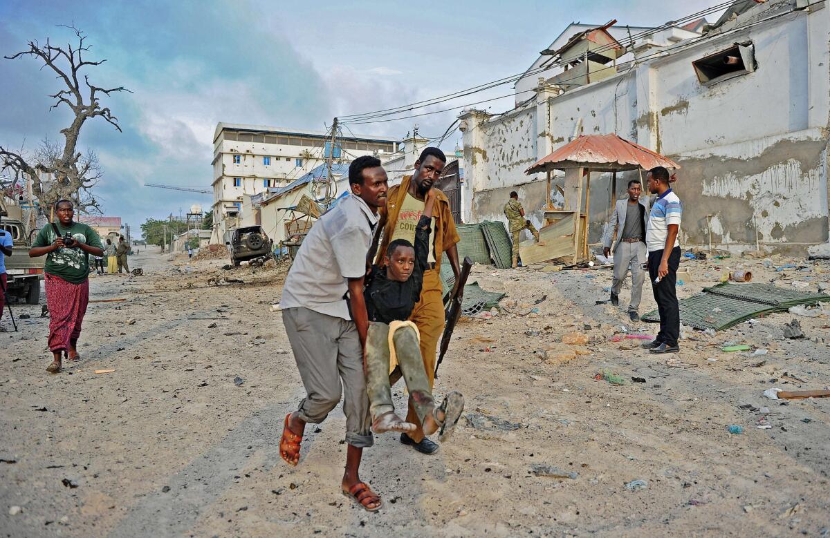 An injured youth is carried away from the scene of a car bomb attack and armed raid by Al Shabab militants on the Maka Mukarramah hotel in Mogadishu, Somalia.