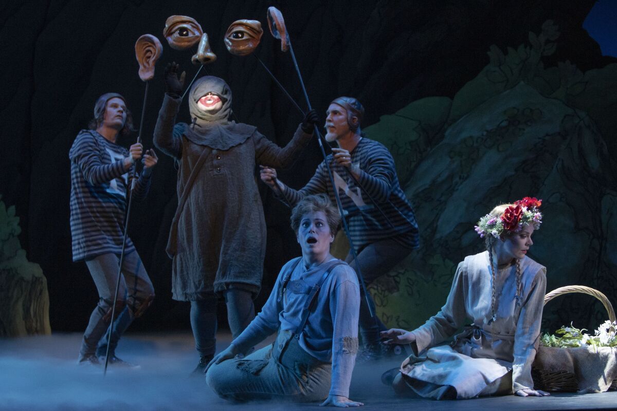 Soprano Devon Guthrie (center, rear) is the Sandman, mezzo-soprano Blythe Gaissert (seated, center) is Hansel, and soprano Sarah Gartland (right) is Gretel in San Diego Opera's "Hansel and Gretel" at the San Diego Civic Theatre. Also pictured are puppeteers Jason James Johnson (left) and Iain Gunn. 