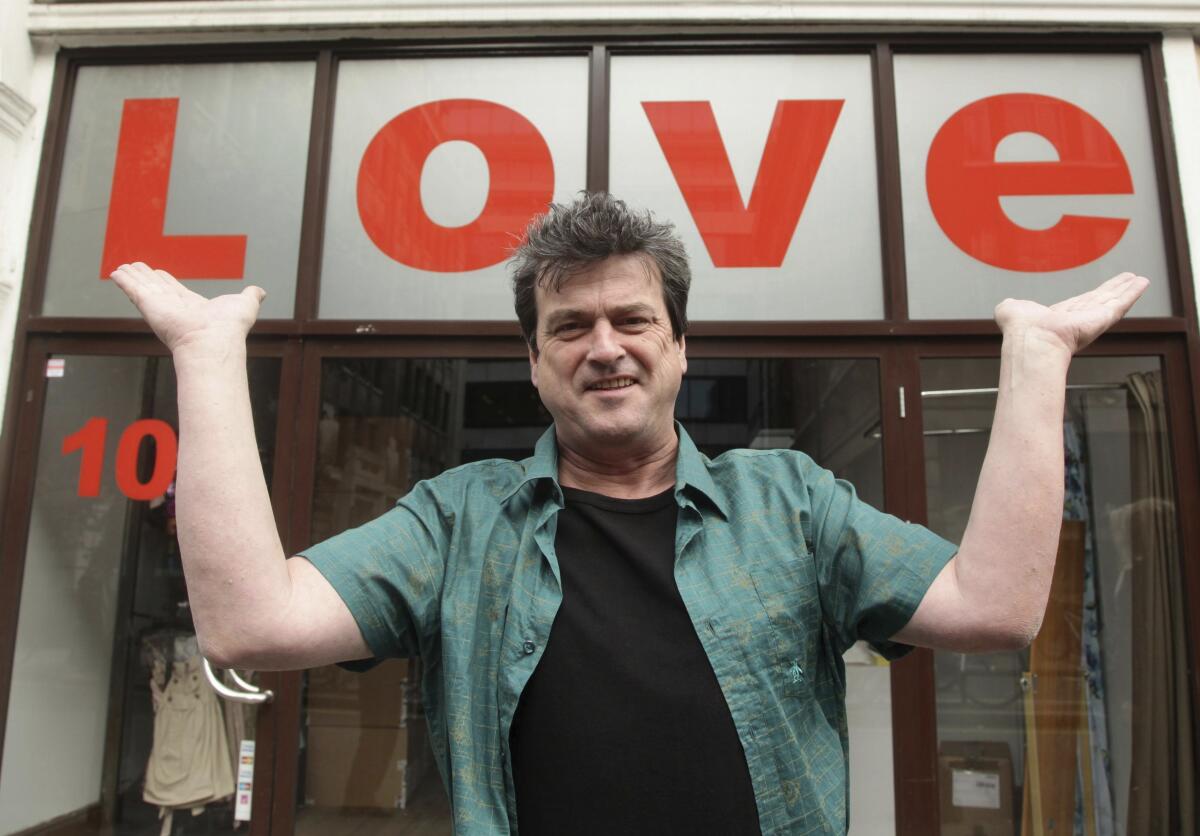 Les McKeown in 2010 stands before a sign that says "Love"