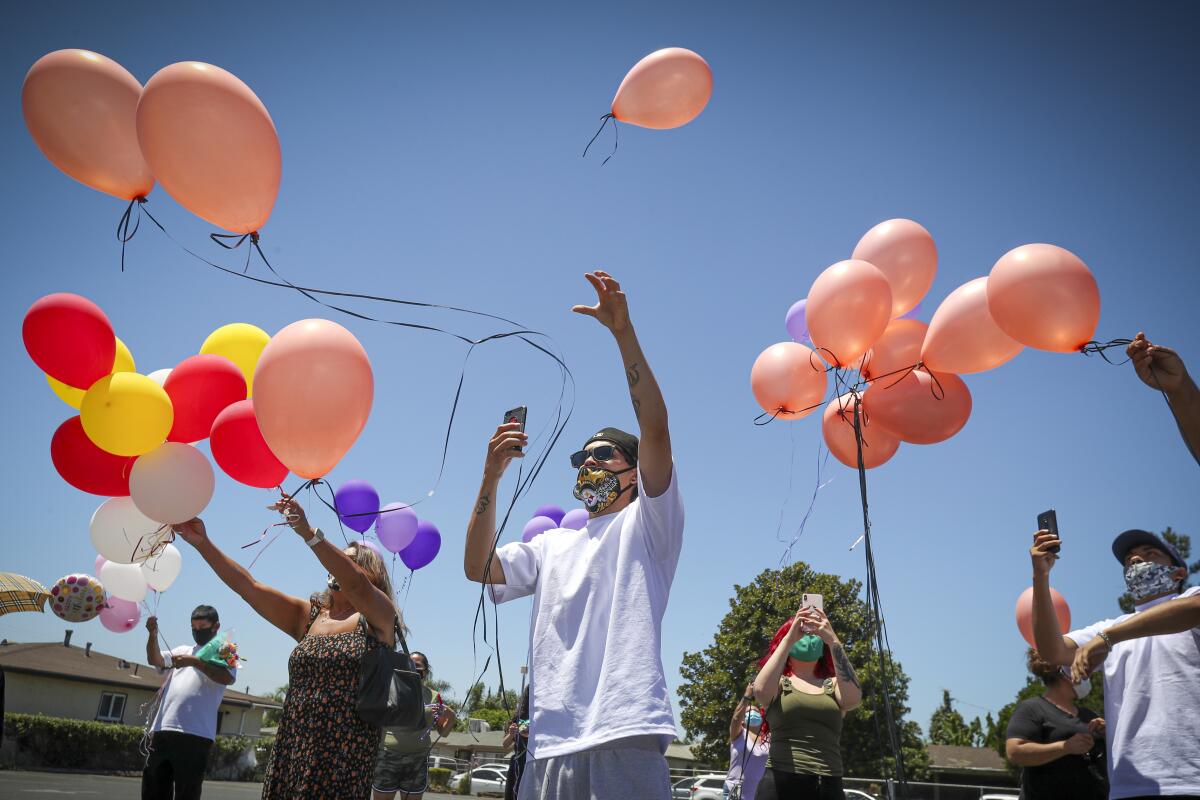 Family and friends release balloons at a memorial service.