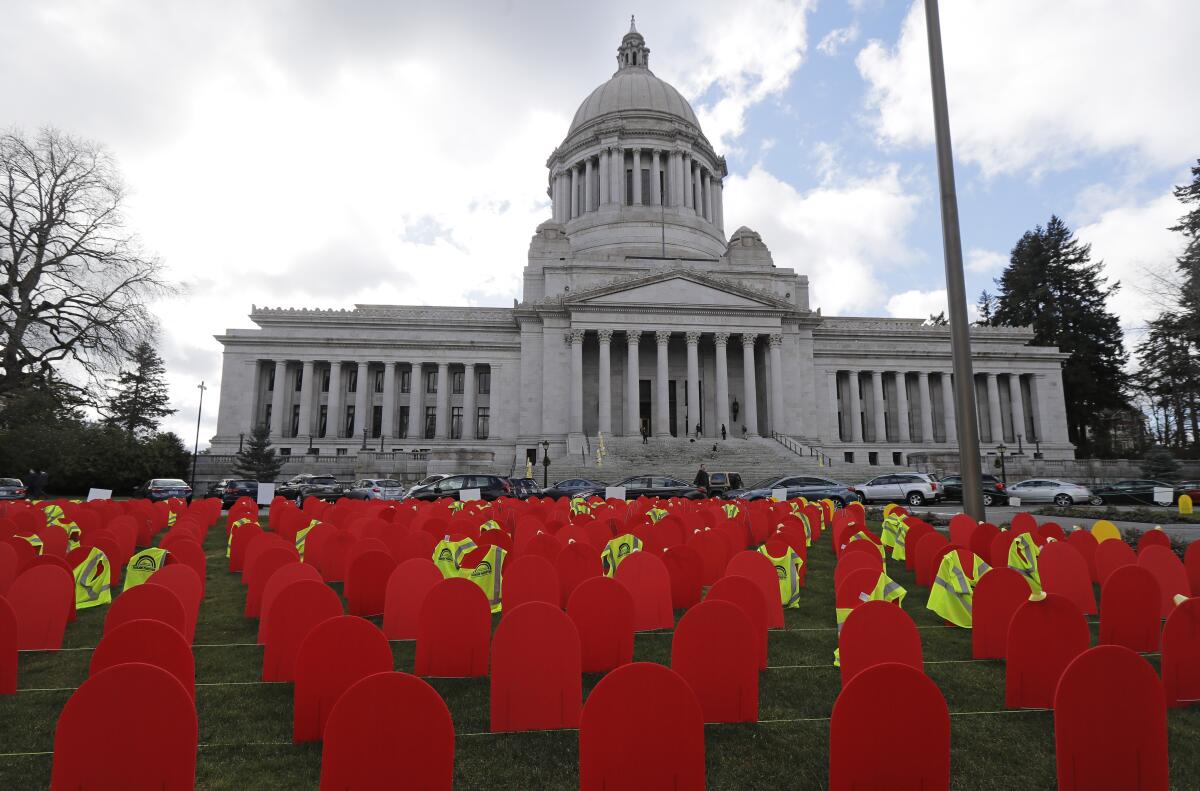 Red mock tombstones in rows in front of a government building.