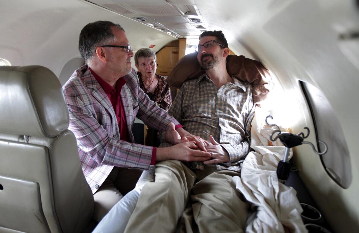 Jim Obergefell, left, and John Arthur are married by officiant Paulette Roberts, rear center, on a plane.