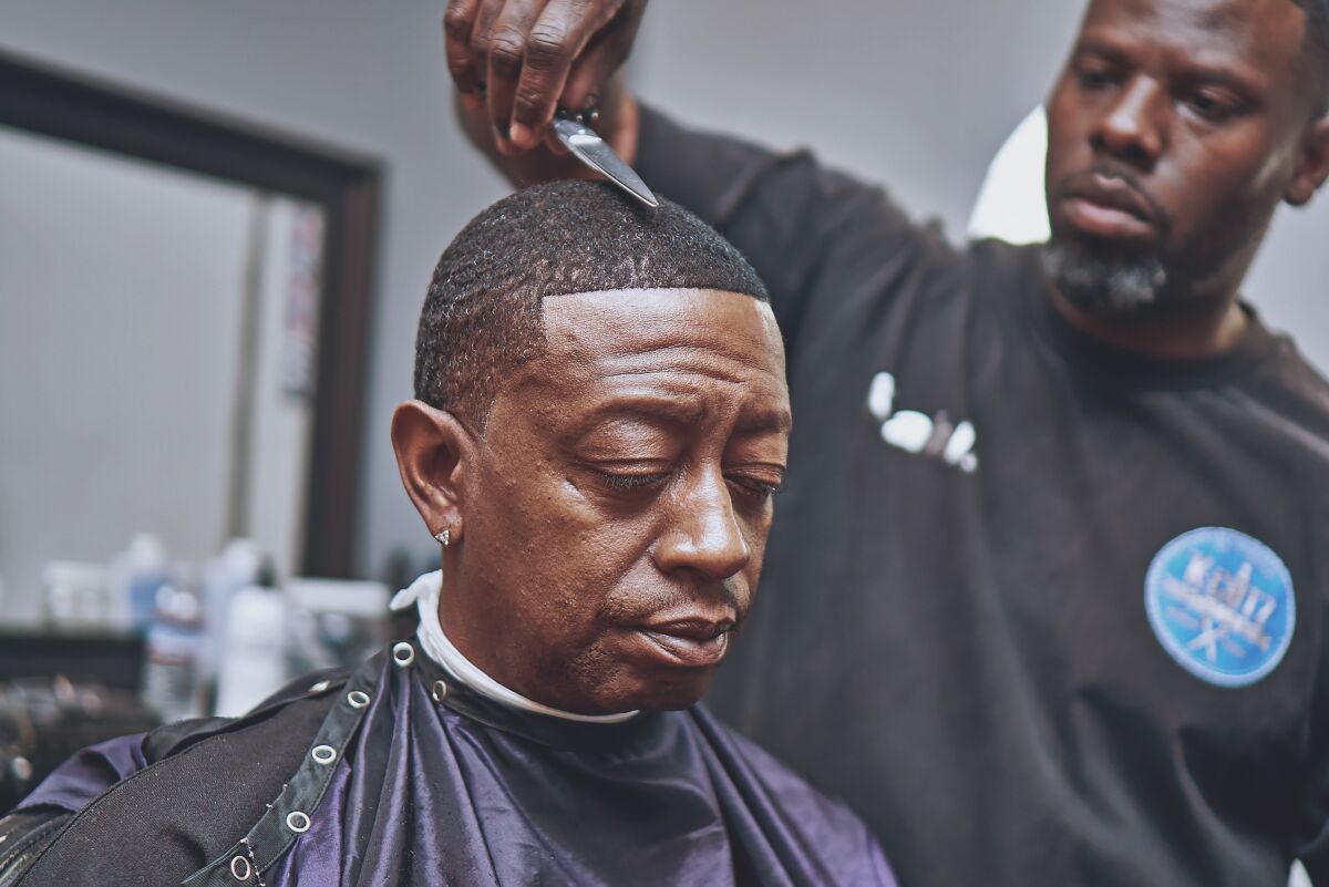 Kahlil Bryant, owner of K-Cutz Barber Shop in San Diego's Rolando neighborhood, works on a customer's hair before social-distancing laws forced him to shut down his shop in March.