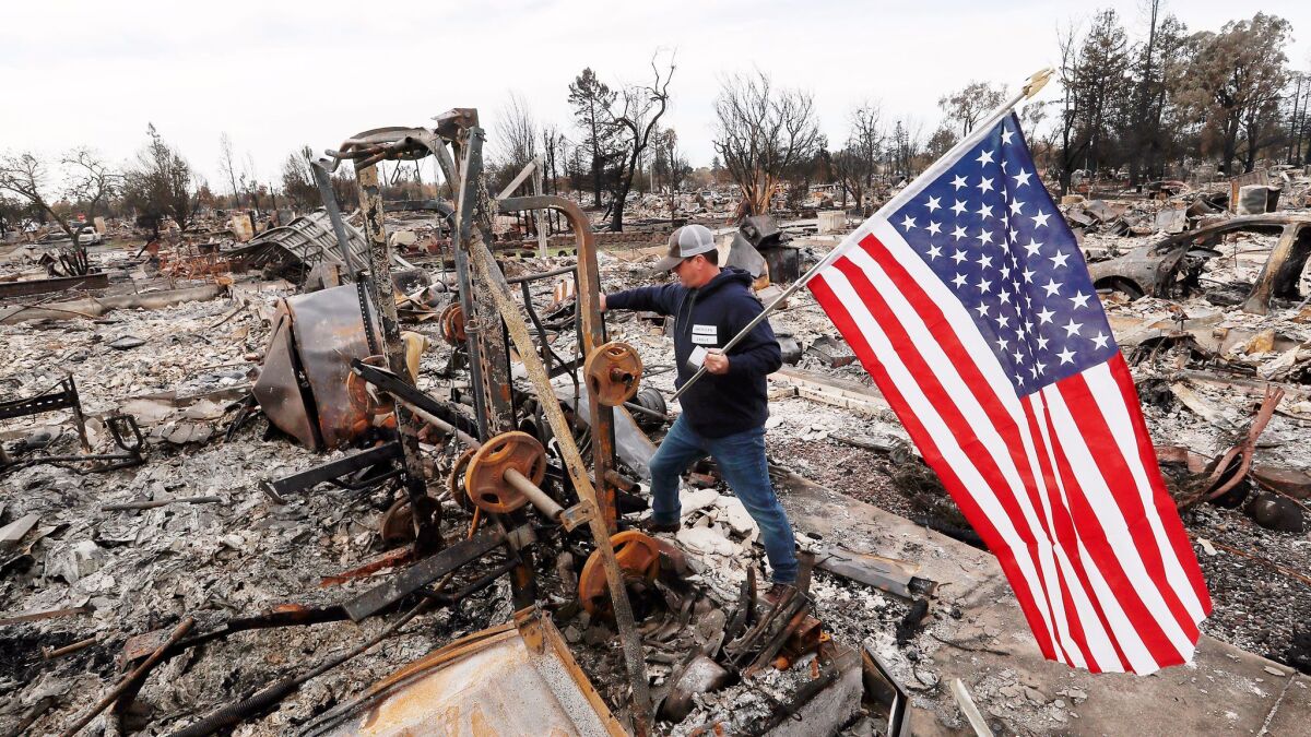 Jason Miller, 45, plants an American flag on the charred remains of his house as residents of Coffey Park. He had lived in the Santa Rosa neighborhood for 23 years before it was destroyed by this month's wildfires.