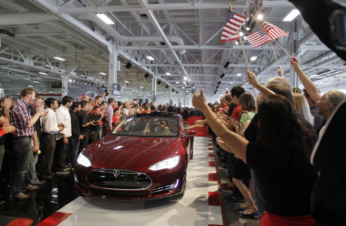 Tesla workers cheer on the first Tesla Model S cars sold during a rally last year at the Tesla factory in Fremont, Calif.