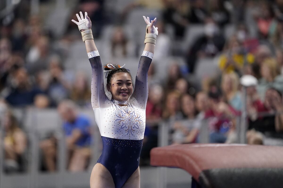 Auburn's Sunisa Lee raises her arms after competing in the vault during the NCAA women's gymnastics championships Thursday, April 14, 2022, in Fort Worth, Texas. (AP Photo/Tony Gutierrez)