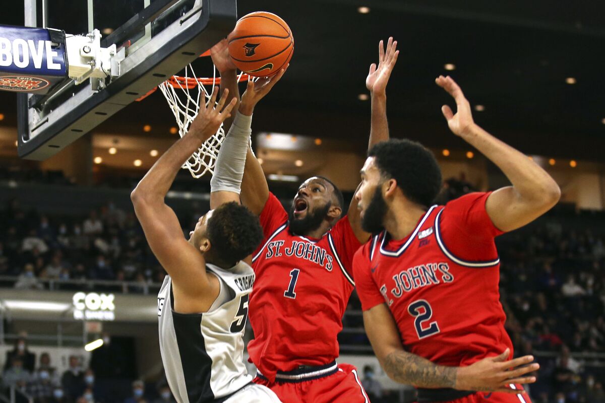 St. John's Aaron Wheeler (1) blocks a shot by Providence's Ed Croswell (5) as Julian Champagnie (2) helps defend on the play during the first half of an NCAA basketball game on Saturday, Jan. 8, 2022, in Providence, R.I. (AP Photo/Stew Milne)