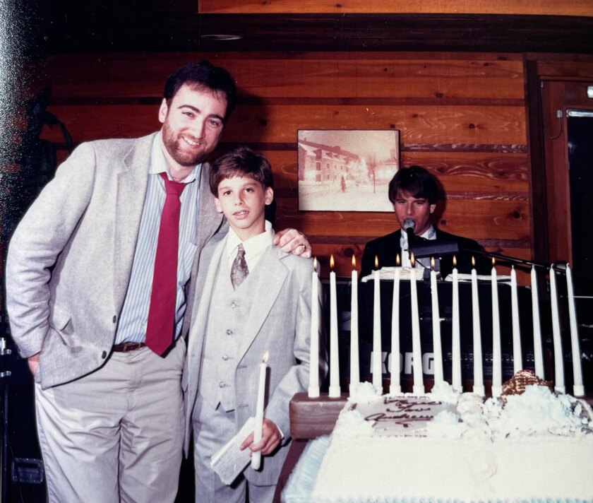 Bill Plaschke smiles with his arm around a young Andrew Ladores.