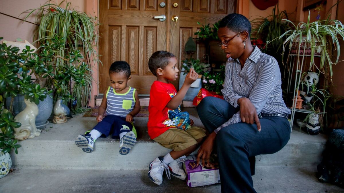 Francis Brown of Sacramento with sons Samson, left, and Samuel outside their daycare. She may no longer qualify for subsidized child care if she gets a small raise or lands a new job that she’s seeking.