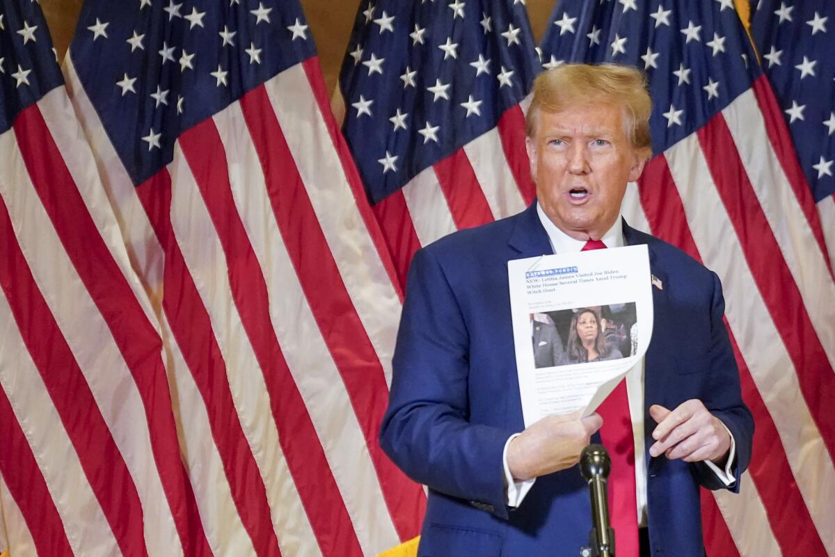 El expresidente Donald Trump sostiene una copia de un reportaje en el que aparece la fiscal 