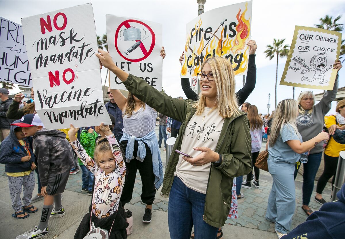 Marissa Toma helps Ciela Chapman hold a sign during school walkout at the Huntington Beach Pier on Monday.