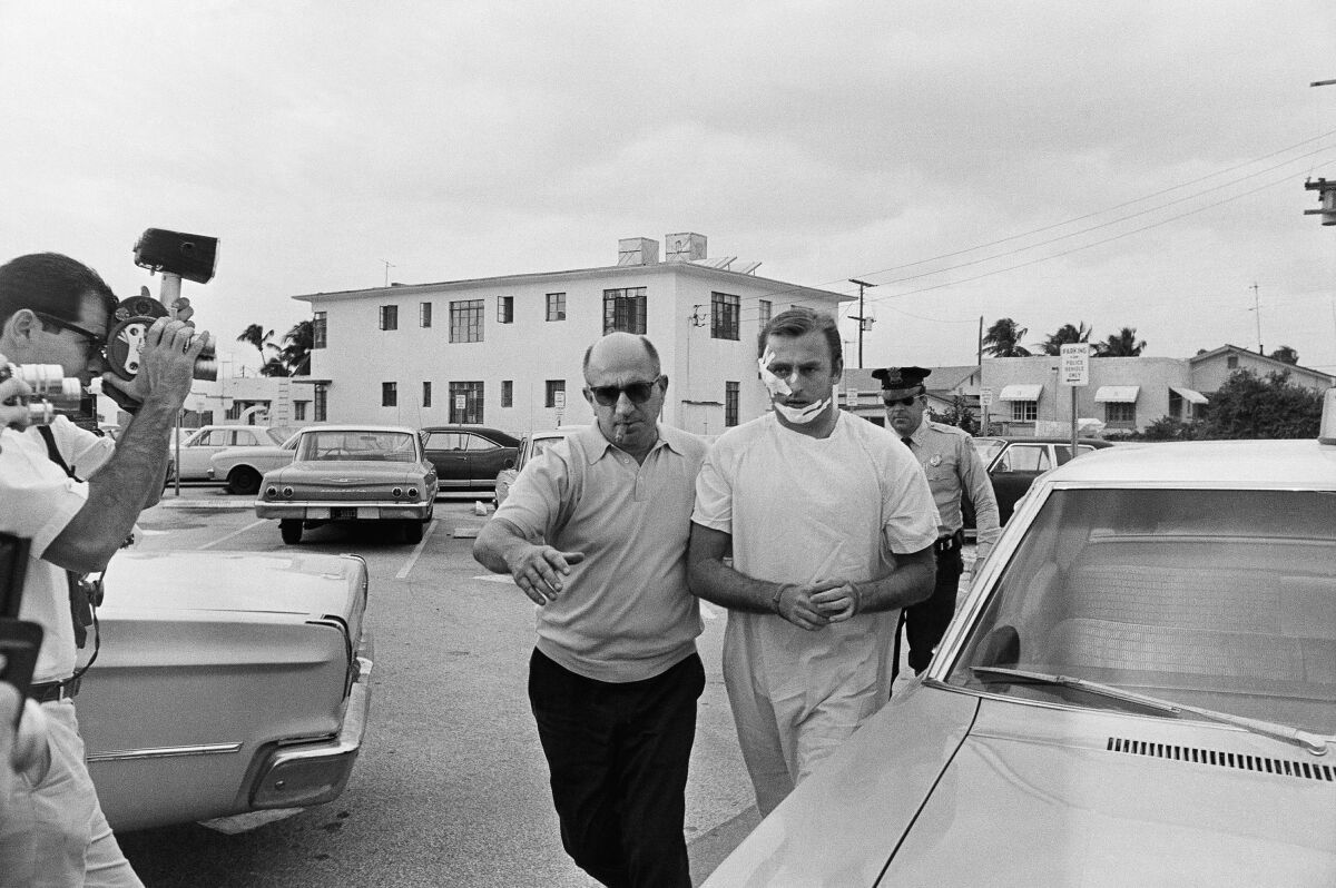  Jack "Murf the Surf" Murphy is escorted into Miami Beach, Fla., police headquarters by a detective in 1968.