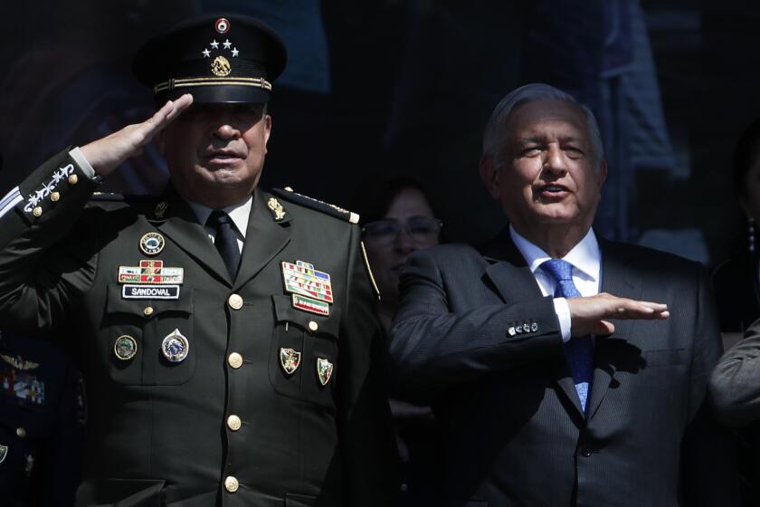 FILE - Defense Secretary Luis Cresencio Sandoval, left, and Mexican President Andres Manuel Lopez Obrador salute during an event marking Army Day at the Zocalo in Mexico City, Feb. 19, 2020. According to seizure figures issued Monday, Dec. 20, 2021, Mexican drug cartels are turning to bigger, more productive labs to churn out increasing quantities of synthetic drugs like meth and fentanyl. Defense Secretary Luis Cresencio Sandoval acknowledged there has been a huge shift by Mexican cartels away from naturally grown drugs like opium and marijuana, where seizures and crop eradication has fallen. (AP Photo/Marco Ugarte, File)
