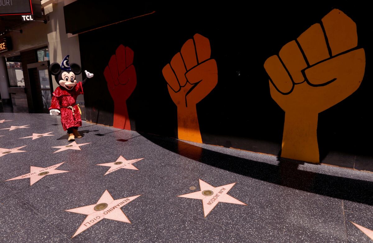 Street performer Javie Rubio, dressed as Mickey Mouse, looks for customers to pose for photos on the empty Walk of Fame.