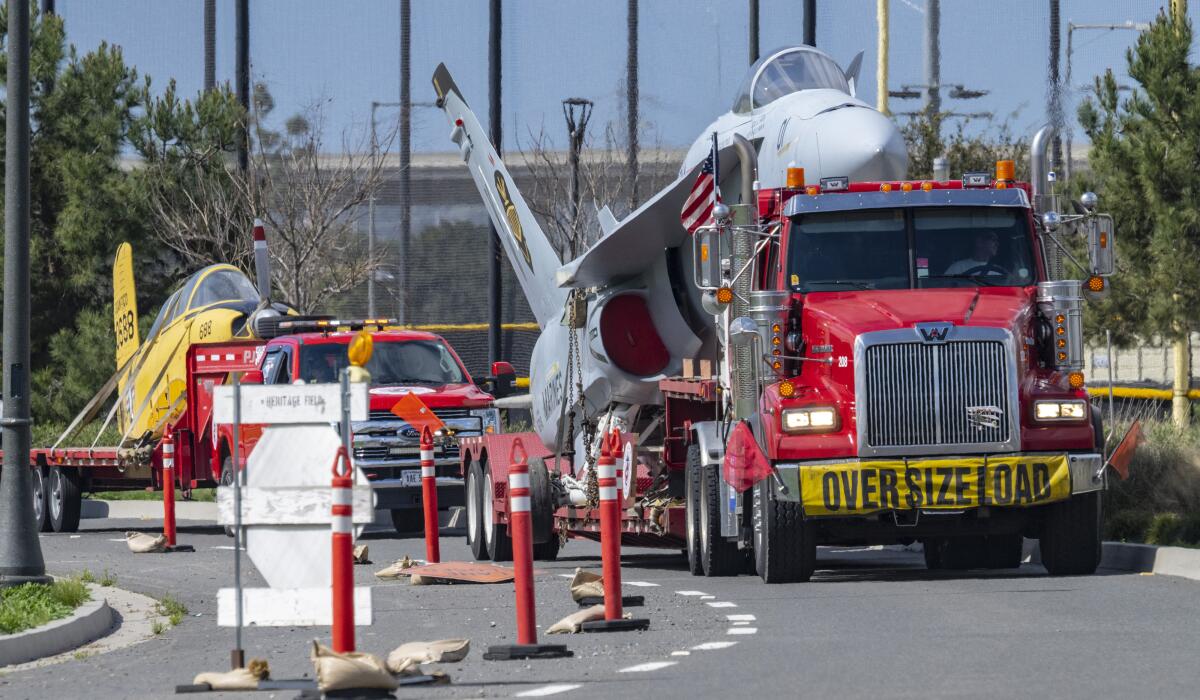 Three aircraft on flatbed trucks make their way through the Great Park in Irvine after departing MCAS Miramar in San Diego