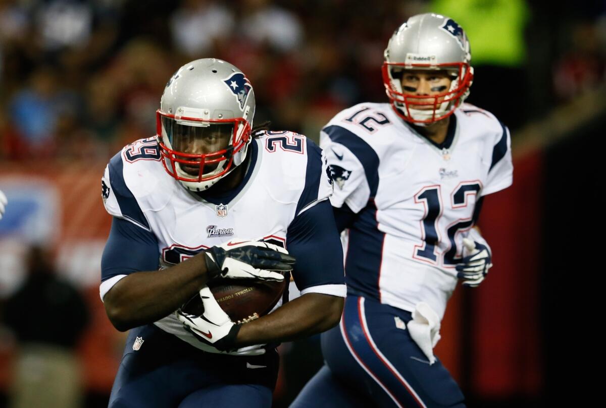 New England running back LeGarrette Blount, left, takes a handoff from quarterback Tom Brady during the Patriots' 30-23 victory Sunday over the Atlanta Falcons.