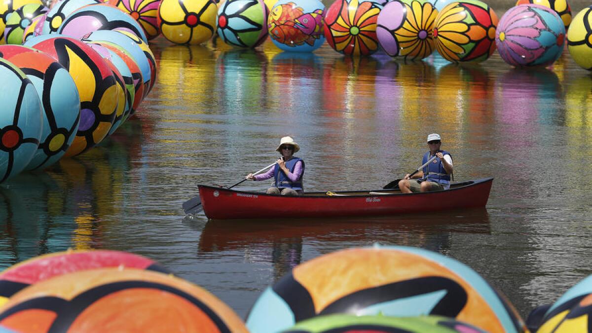 El proyecto de arte público "Esferas en MacArthur Park" está cubriendo el lago del parque en un mar de esferas coloridas. Dos voluntarios remaron a través de la atracción el sábado por la mañana.