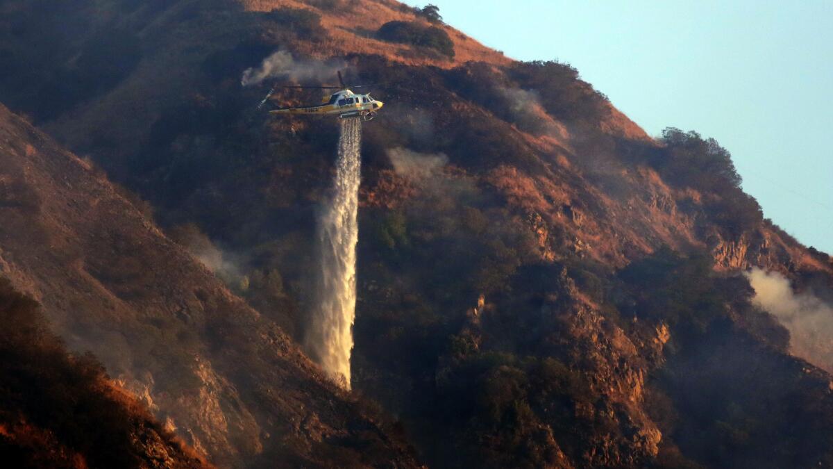 A helicopter drops a load of water on a brush fire that broke out in the hills above San Dimas early Wednesday.