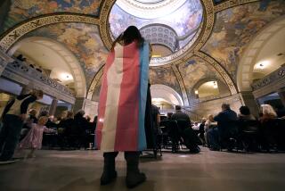 FILE - Glenda Starke wears a transgender flag as a counter protest during a rally in favor of a ban on gender-affirming health care legislation, March 20, 2023, at the Missouri Statehouse in Jefferson City, Mo. Missouri’s Republican Attorney General Andrew Bailey and the families of transgender children are in court fighting over whether a new law banning minors from receiving gender-affirming health care will take effect as scheduled on Monday, Aug. 28. (AP Photo/Charlie Riedel, File)