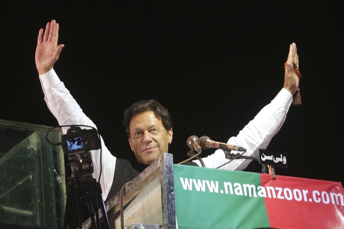 Imran Khan raises his arms while speaking at a rally