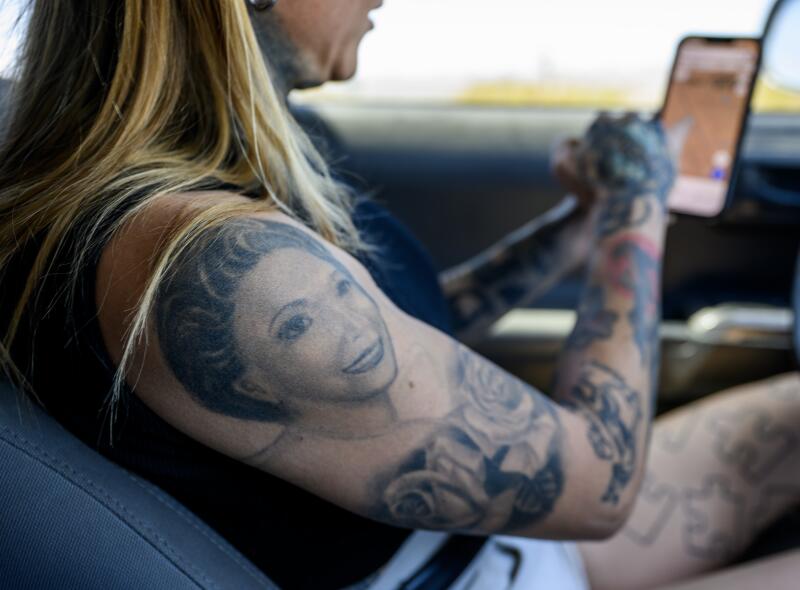 Image shows a tattoo of Wall's grandmother on her right arm as she looks at a smartphone