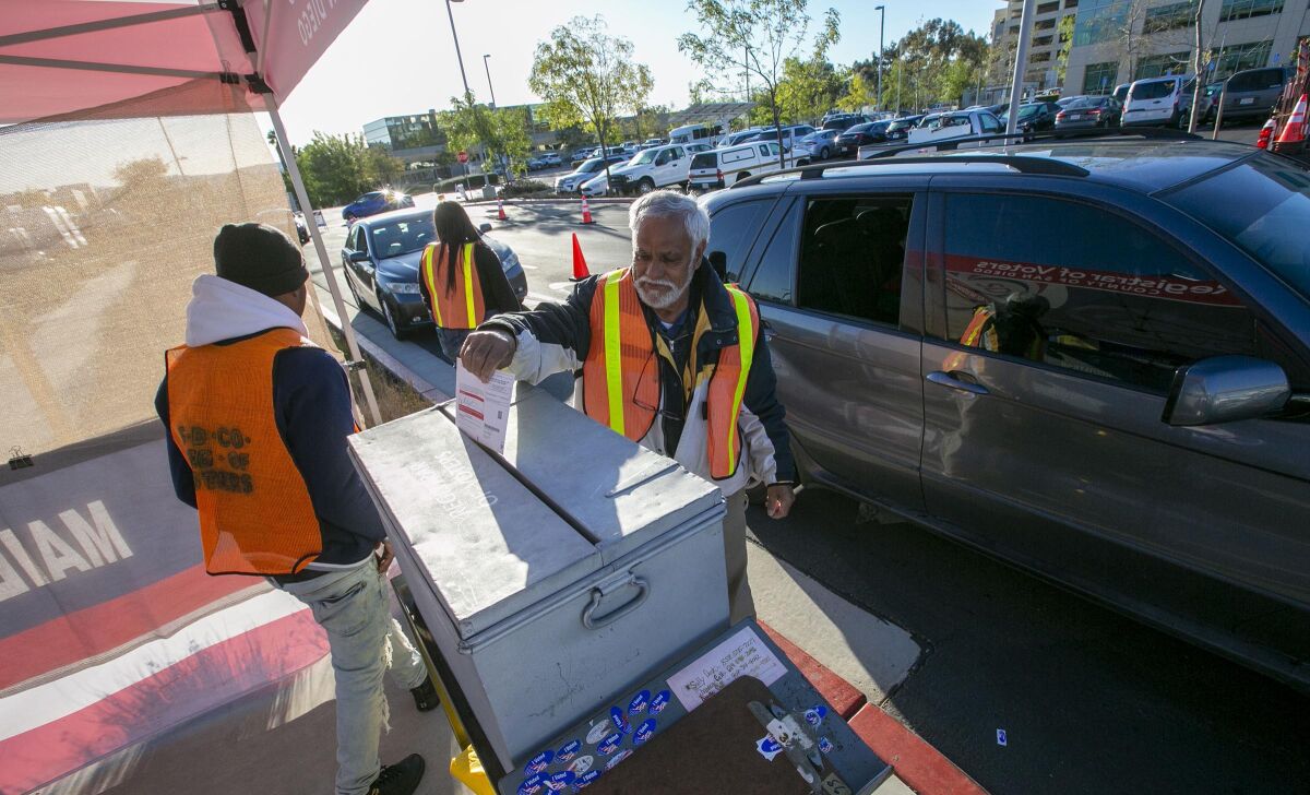 Election workers collected ballots from drive-up voters in Kearny Mesa on election day on March 3, 2020.