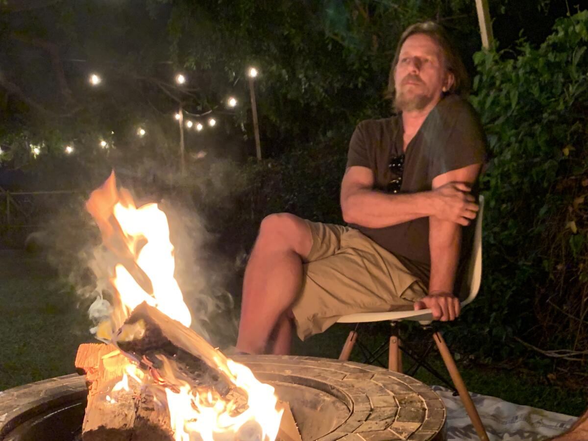 John Albert sits next to a firepit