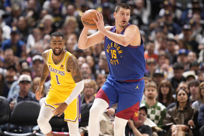 Denver Nuggets center Nikola Jokic collects the ball as Los Angeles Lakers guard D'Angelo Russell watches during the second half of an NBA basketball game Tuesday, Oct. 24, 2023, in Denver. (AP Photo/David Zalubowski)