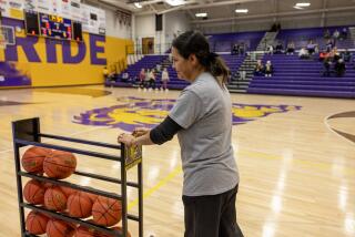 DENISON, IOWA - JANUARY 16, 2024: Vicenta Lira Cardenas, a janitor at Denison High School, rolls out the rack of basketballs for the visiting team during the girls basketball game on January 16, 2024 in Denison, Iowa. Her daughter plays on the team. The school is 60% Latino and the town itself is 50% Latino. She voted for Vivek Ramaswamy during the Iowa caucuses. (Gina Ferazzi / Los Angeles Times)