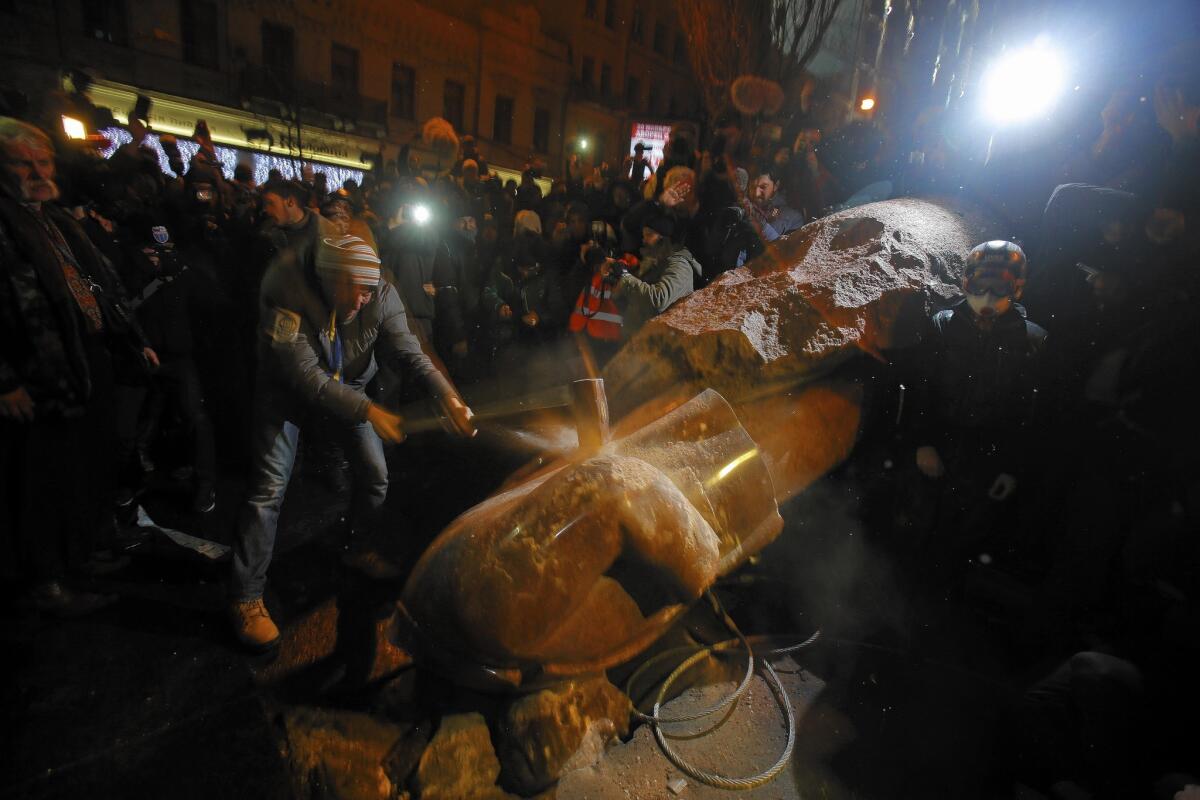 A protester brings down a sledgehammer on the statue of Lenin toppled by the crowd during antigovernment protests in Kiev, Ukraine.