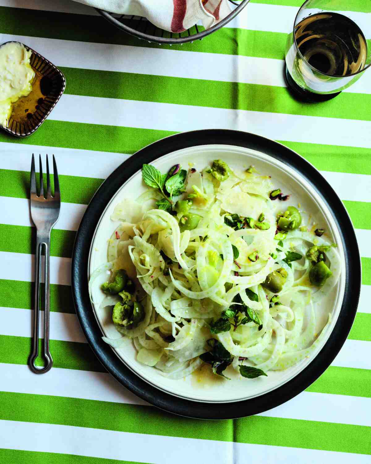 A striped tablecloth with a plate of salad and a fork.