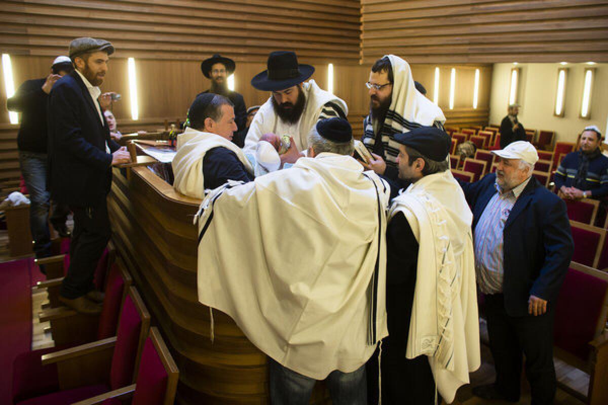 An infant boy is surrounded by rabbis and relatives at a Jewish ritual circumcision ceremony in Berlin in October.