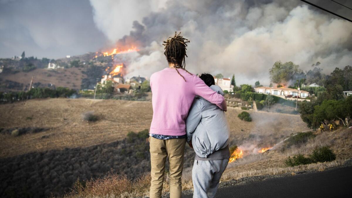Residents with a home on Las Trancas Canyon Road watch as the Woolsey fire approaches their home Friday morning. Minutes later the area was engulfed by a rotating column of fire.
