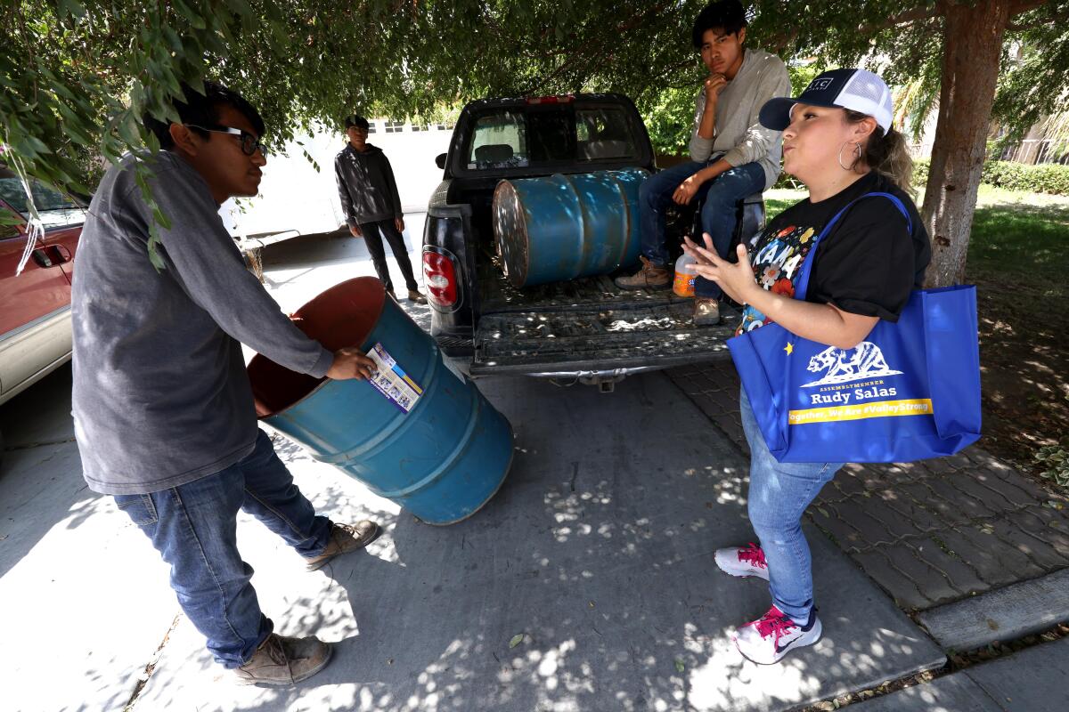 Flor Olvera talks with young men near a pickup truck while canvassing for Rudy Salas.