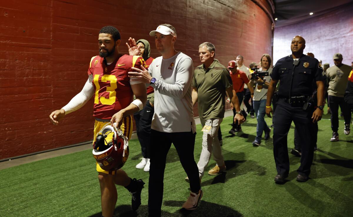USC quarterback Caleb Williams and coach Lincoln Riley make their way to the field at the Coliseum.