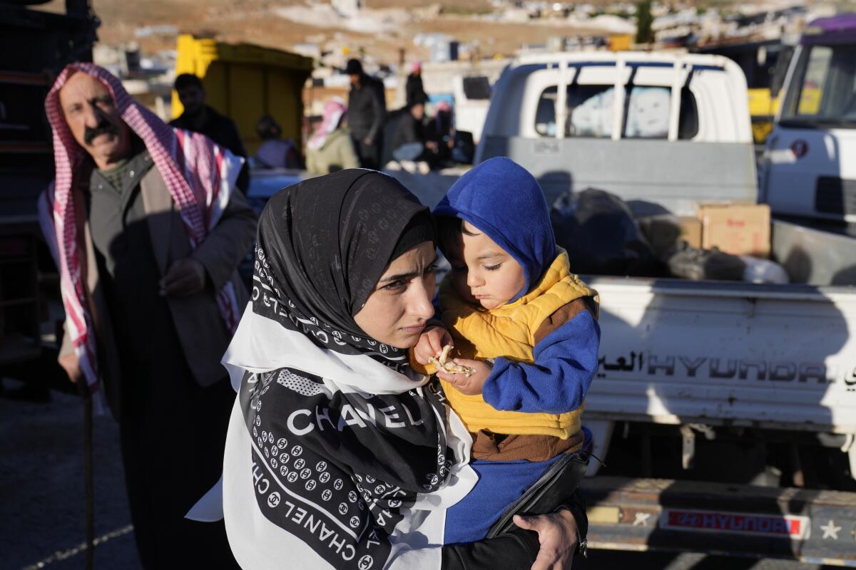 Una refugiada siria carga a su hijo en brazos mientras se prepara para volver a su país 