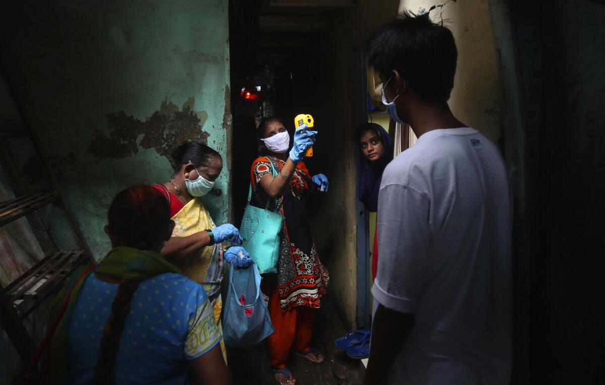 A healthcare worker checks people for COVID-19 symptoms in Dharavi, one of Asia's biggest slums, in Mumbai, India.