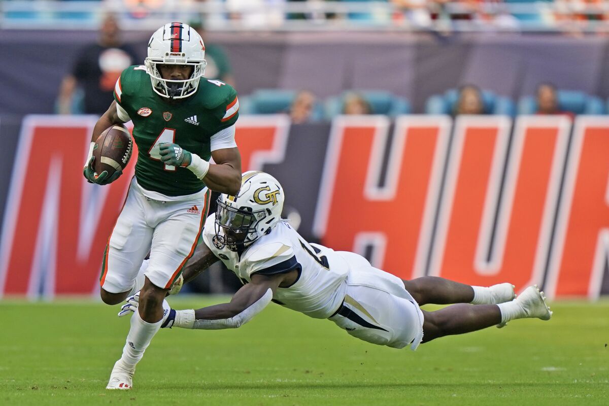 Miami running back Jaylan Knighton (4) avoids a tackle by Georgia Tech linebacker Ayinde Eley during the first half of an NCAA college football game, Saturday, Nov. 6, 2021, in Miami Gardens, Fla. (AP Photo/Wilfredo Lee)