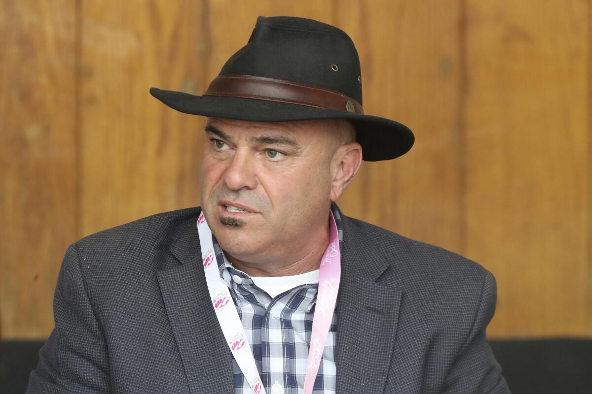 Horse trainer Peter Miller looks on from the stables at Churchill Downs in Louisville, Ky.