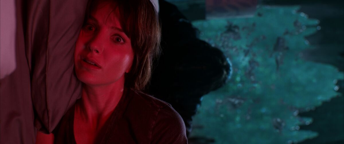 A young woman looking terrified, her face illuminated in red