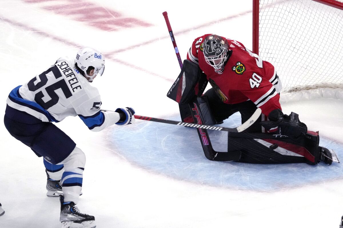 Chicago Blackhawks goaltender Arvid Soderblom, right, stops a shot by Winnipeg Jets center Mark Scheifele during the third period of an NHL hockey game in Chicago, Friday, Dec. 9, 2022. The Jets won 3-1. (AP Photo/Nam Y. Huh)