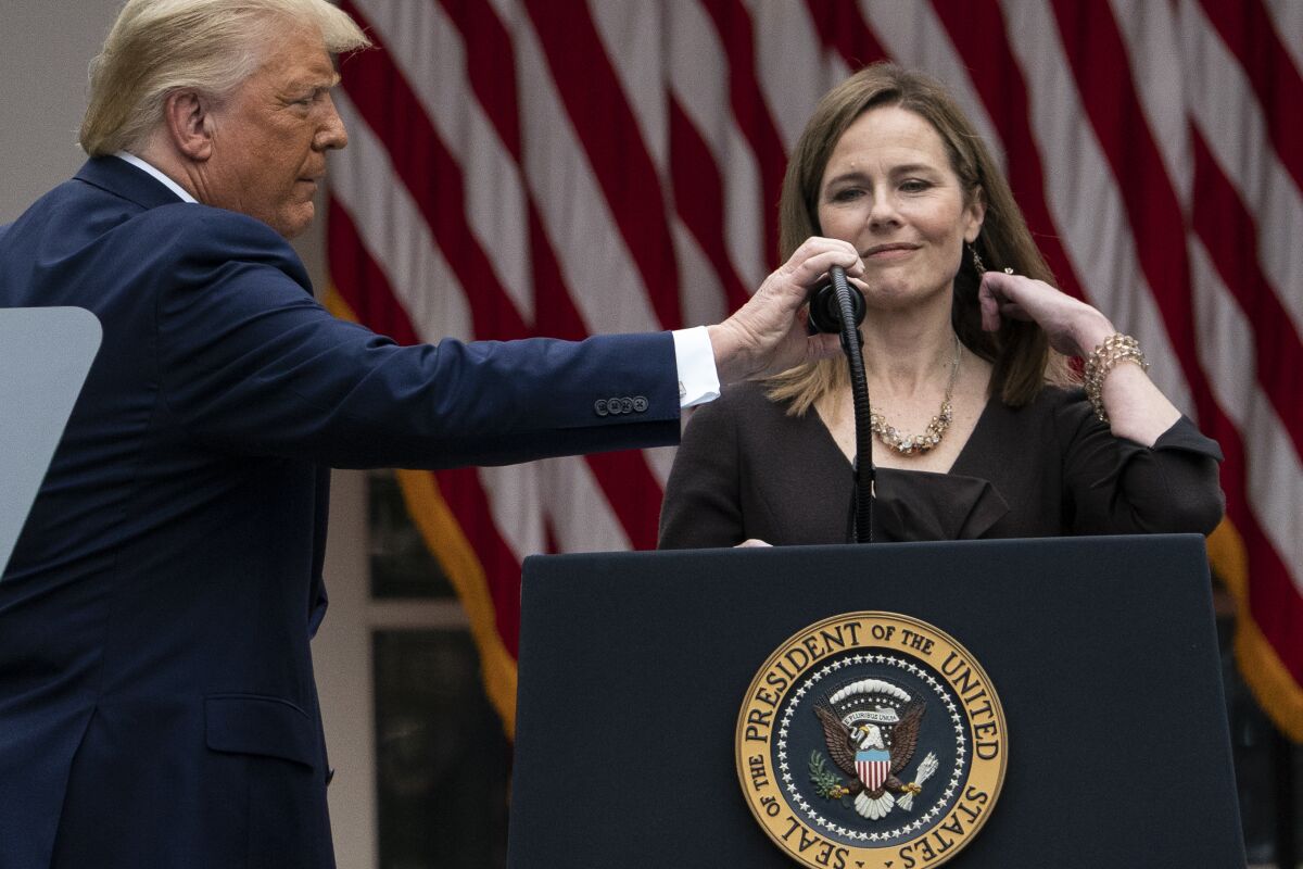 President Trump adjusts a microphone for Judge Amy Coney Barrett