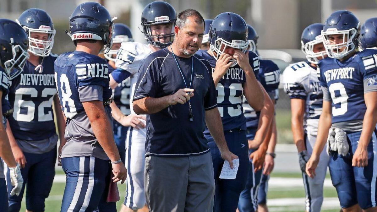 Newport Harbor High first-year coach Peter Lofthouse, center, instructs his players during football practice on Aug. 16.